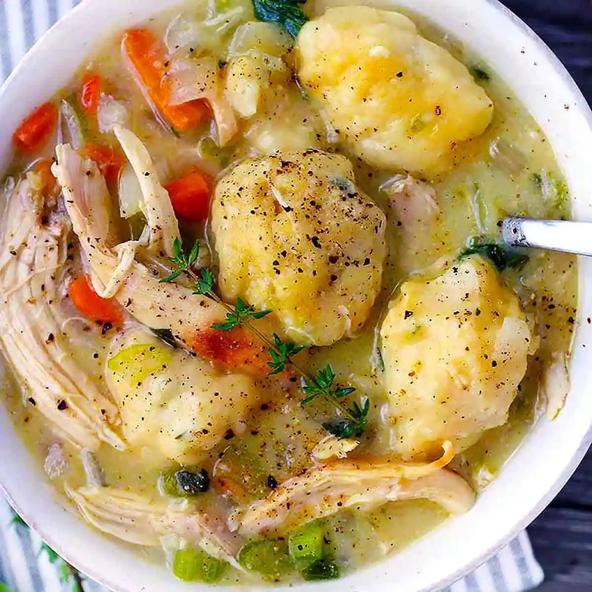 Easy Chicken and Dumplings Recipe From Scratch 2 A rustic bowl of creamy chicken and dumplings garnished with fresh thyme leaves